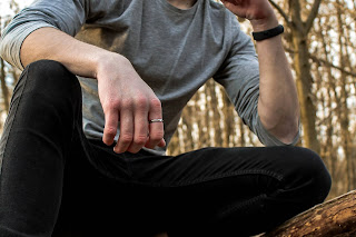 A man sitting outdoor, wearing a band ring.