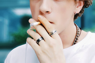 A smoking man wearing rings.