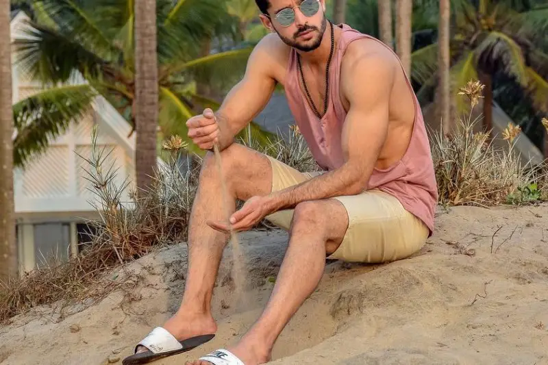A men wearing short, sleeveless t-shirt with shades on beach
