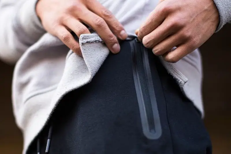 A man opening side zio of his jogger.