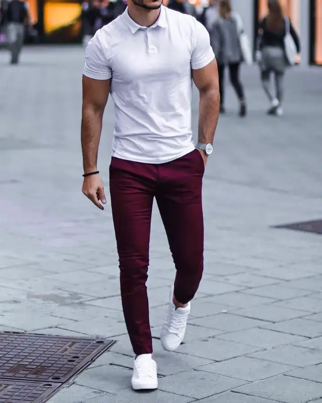A man wearing white polo and maroon chinos.