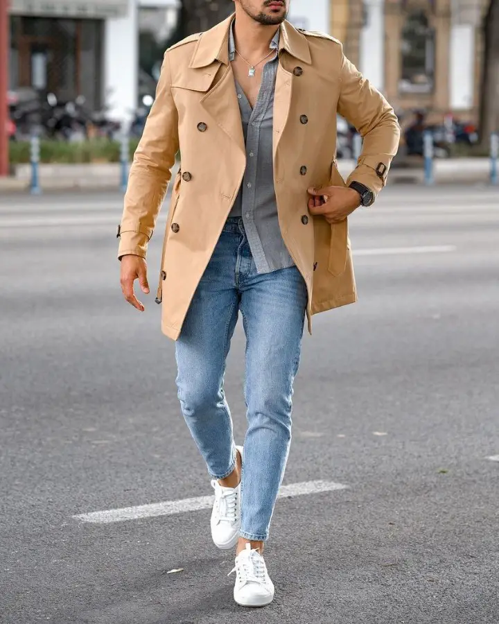 A man wearing a Long coat, jeans and a shirt combo outfit.