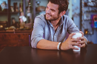 A men sitting alone in a cafe and smiling