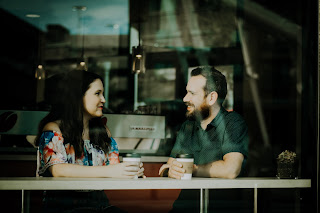 A man and woman making eye contact, while sitting in a cafe.