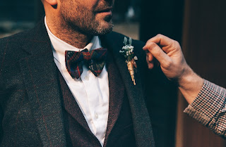 A men appreciating the design of boutonniere of other men's suit.