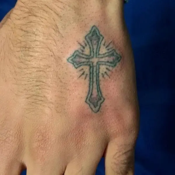 Cross tattoos between thumb and index finger