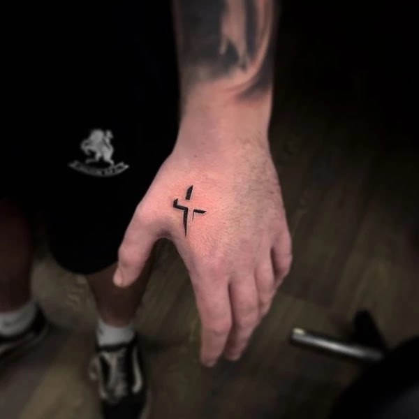 Cross tattoos between thumb and index finger