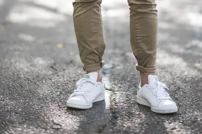 A guy wearing a jeans by rolling its cuff.