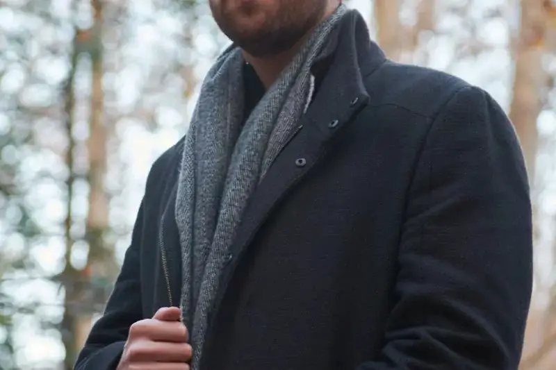A men hide his scarf under coat.